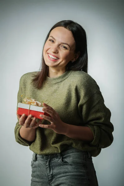 Retrato de mulher jovem segurar presente no estilo de cor de Natal. Sorrindo menina feliz onn um luz azul-verde fundo Fotografias De Stock Royalty-Free