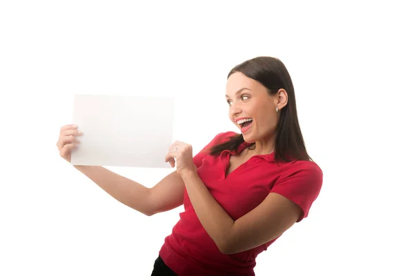 Красивая улыбающаяся молодая женщина удивлена белой рекламной рамкой - белой бумагой формата А4, пустой для текста Лицензионные Стоковые Изображения