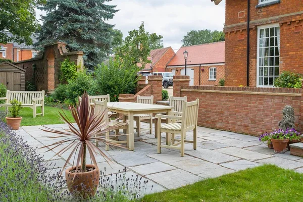 Large UK property, house with back garden, wooden furniture table and chairs on patio terrace