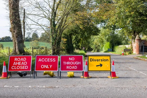 Road closed signs on a UK country road with yellow diversion sign