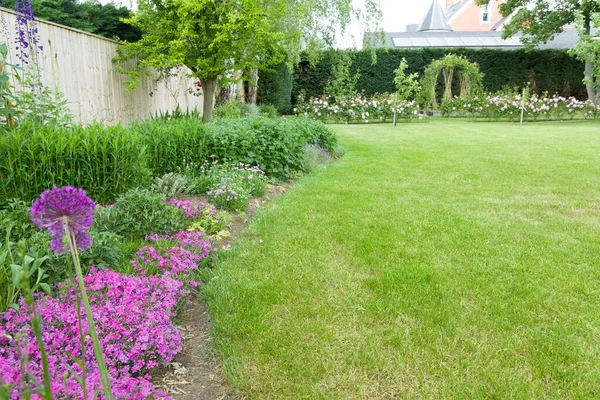 Large English garden in early summer or late spring with flowers in border and lawn. Example of landscaped garden design and gardening, UK — Stock Image Large English Garden Early Summer Late Spring Flowers Border Lawn Royalty Free Stock Images