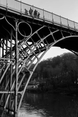 TELFORD, İngiltere - 18 Şubat 2013. Demir Köprü 'yü geçen bir grup turist, sanayi devriminin başlangıcında Ironbridge Vadisi üzerine inşa edilen ilk dökme demir kemer köprüsü oldu. Tek renkli resim.