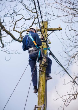 CONWY, İngiltere - 29 Şubat 2012. BT Openreach telekomünikasyon mühendisi telefon hattını tamir ediyor. Galler, Snowdonia 'da bir telgraf direği üzerinde çalışan teknisyen..