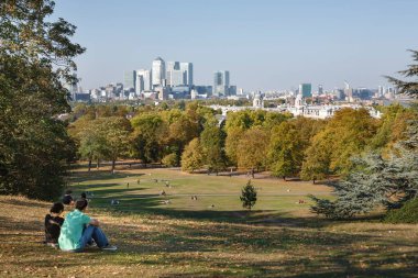 Londra, İngiltere - Ekim 03, 2011. Sonbaharda Greenwich Park 'ta oturan çift Canary Wharf ve London Skyline manzarasının keyfini çıkarıyorlar.