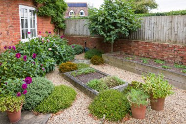 Yazın sonlarında küçük bir kır evi bahçesinde meşe yatakları ve sert peyzaj işleri vardı. İngiliz bahçeleri, İngiltere