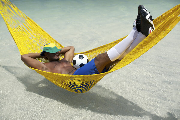 Brazilian Soccer Player Relaxing with Football in Beach Hammock