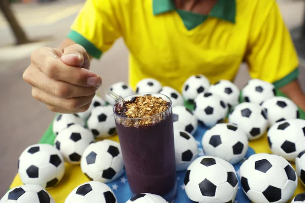 Jugador de fútbol brasileño comiendo Acai con balones de fútbol — Foto de Stock