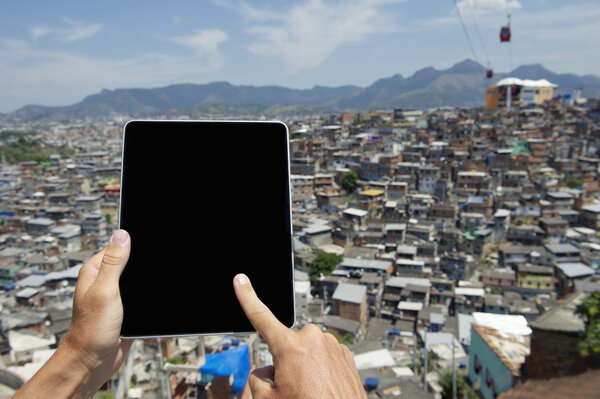 Руки с помощью планшета в бразильском Фавела городских трущобах Рио-де-Жанейро
