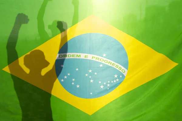 Brazilian Celebrating Arms Raised Behind Flag — стокове фото