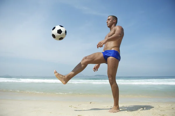 Спортивный молодой бразилец, пинающий футбол Рио-Бич — стоковое фото