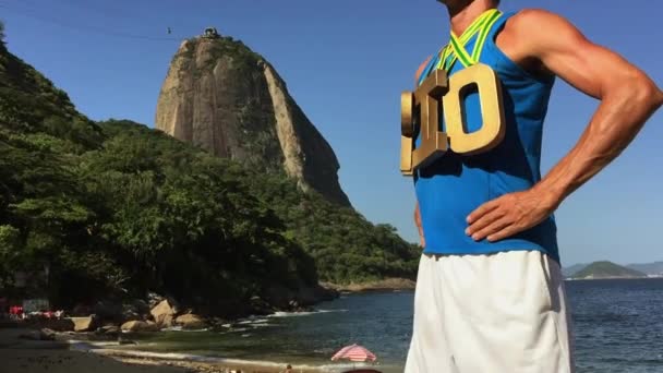 Zlatá medaile Rio sportovec stojící na Sugarloaf Mountain — Stock video