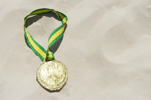 Zlatá medaile s mašlí barvy Brazílie v písku — Stock fotografie