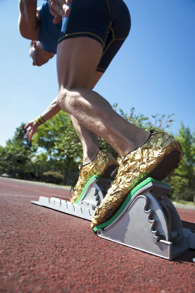 Спортсмен в золотому взутті на стартових блоках — стокове фото