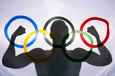 Olimpiyat bayrağı arkasında atlet silüeti