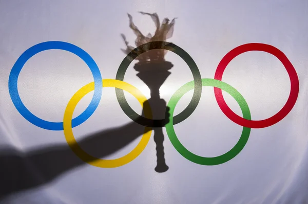Silueta de la antorcha deportiva detrás de la bandera olímpica Imagen de archivo