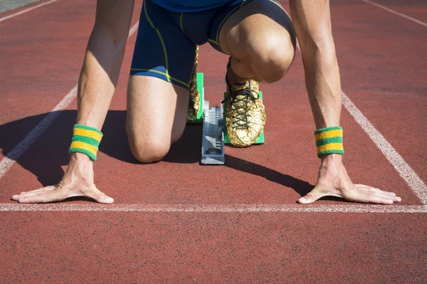 Atleta agachado em blocos de partida de pista de corrida — Fotografia de Stock