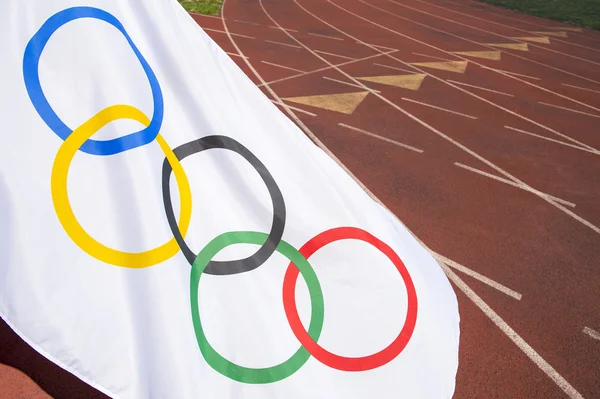 Bandera Olímpica ondeando en pista de atletismo —  Fotos de Stock