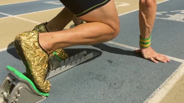 Sportovec v zlaté boty na startovací bloky — Stock video