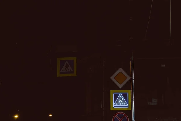 pedestrian crossing sign glowing in the dark city street night