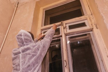 İşçi ressam pencereyi bant boyama işi için hazırlıyor 