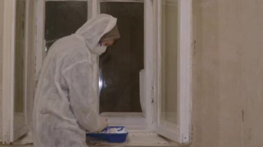 Koruyucu takım elbiseli dansçı zehirli camları boyuyor. 