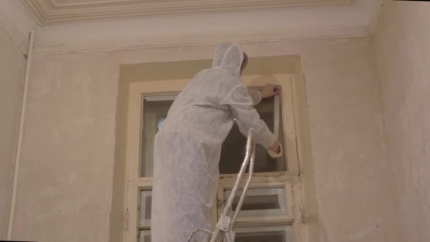 Pintor trabajador prepara ventana para pintar cinta adhesiva — Vídeo de stock