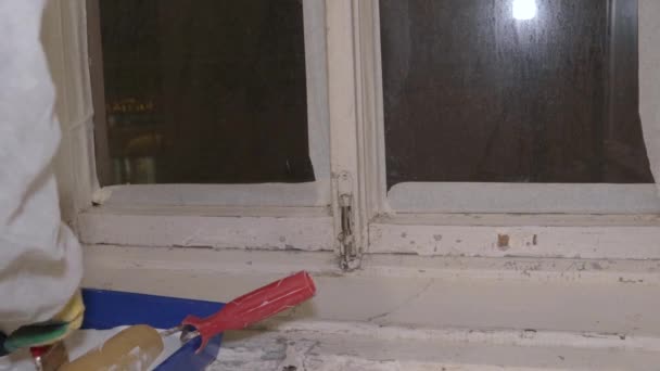 Maler in Schutzanzug und Atemschutzhandschuhen bemalt Fensterpinsel — Stockvideo