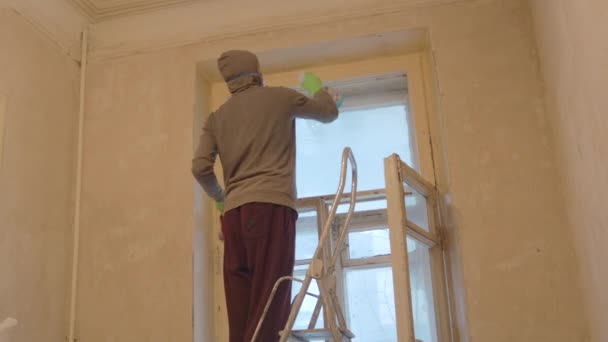 Hombre trabajador ventana limpia marcos de madera en guantes y máscara — Vídeo de stock