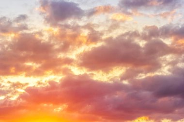 Gün batımında bulutlar ve güneş ışınları rüzgâr bulutları arasında. dalgalı bulutlar. Konsept hava arkaplanı. Turuncu sarı pembe.