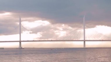 Nehrin üzerinde geniş bir köprü ve sürüş arabaları var. dinamik hareket. Konsept ulaşım şehri. Gri ve turuncu renkli..