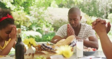 Çok nesildir Afro-Amerikan ailesi bahçede birlikte vakit geçiriyorlar, yemek masasında oturuyorlar, gözleri kapalı dua ediyorlar, ağır çekimde.. 