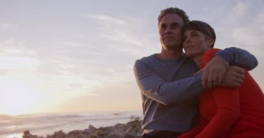 Kafkasyalı çift, gün batımında deniz kenarında vakit geçirmeyi seviyor. Yavaş çekimde kucaklaşıyorlar. Sahilde erken emeklilik.