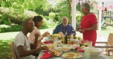 Çok nesildir Afro-Amerikan ailesi bahçede birlikte vakit geçiriyor, yemek masasında oturuyor, masayı temizliyor, arka planda oynayan çocuklar, yavaş çekimde..