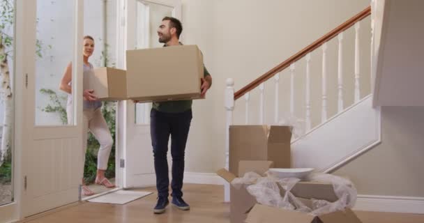 白人の魅力的なカップルは 新しい家に移動し ドアを通って歩くと段ボール箱を運ぶと 地面にそれらを置く スローモーションで — ストック動画