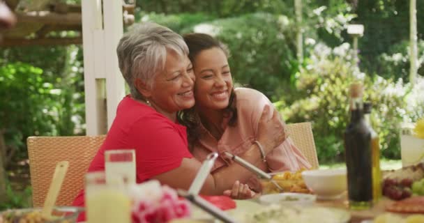 老年非洲裔美国妇女花时间在花园里 与家人一起坐在餐桌前 抱着女儿 动作缓慢 — 图库视频影像