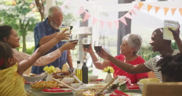 多代非洲裔美国人家庭一起在花园度过时光 坐在餐桌前 慢吞吞地举杯 — 图库视频影像