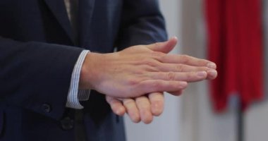 Erkek iş dünyasının orta kesiminde, modern ofiste çalışarak elleri yavaş çekimde sterilize ediyor. Coronavirus Covid 19 salgını sırasında işyerinde sağlık ve hijyen.