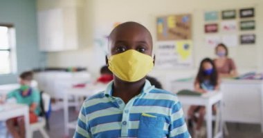 Yüz maskesi takmış, kameraya bakan bir çocuğun portresi. Eğitim, Covid19 Coronavirus salgını sırasında sağlık güvenliğine geri döndü.