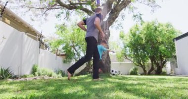 Beyaz bir adam oğluyla bahçede futbol oynayarak vakit geçiriyor. Covid 19 koronavirüs karantina süresince sosyal mesafeler.