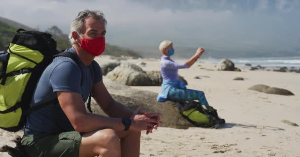 Senior Wandelaar Man Draagt Gezichtsmasker Met Rugzakken Zittend Een Rots — Stockvideo