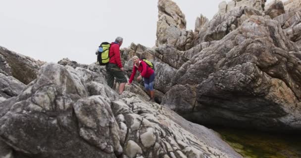 Sırt Çantaları Yürüyüş Direkleriyle Dağlarda Kayalara Tırmanırken Ele Tutuşan Yaşlı — Stok video