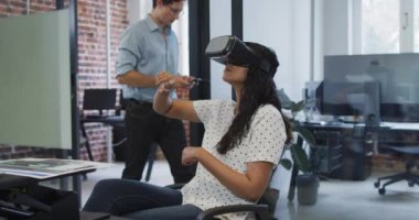 Karışık ırk kadın iş dünyası yaratıcısı, modern ofis Waring VR kulaklığı, yavaş çekimde parmaklarına dokunuyor. Yaratıcı iş modern ofis.