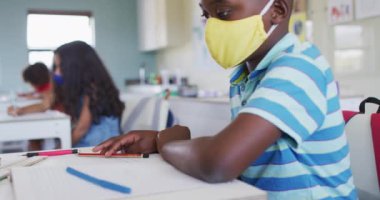 Yüz maskesi takan, dirseğine hapşıran bir öğrenci. Eğitim, Covid19 Coronavirus salgını sırasında sağlık güvenliğine geri döndü.
