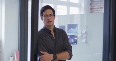 Kafkas erkek iş dünyasının portresi, modern ofiste çalışıyor, kapıya yaslanıyor, kameraya gülümsüyor, ağır çekimde. Yaratıcı iş modern ofis.