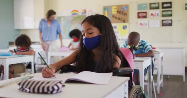 白人女性教師は学校でフェイスマスクを着用し 学校の教室で子供たちに教える Covi19コロナウイルスパンデミックの際の学校の安全性への教育 — ストック動画