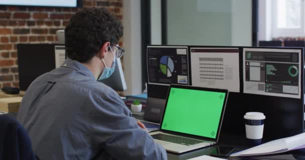 白种人男性商业创意 在现代办公室工作 戴着面具 使用带有绿色屏幕的笔记本电脑 动作缓慢 Coronavirus Covid 19大流行病期间工作场所的健康和卫生 — 图库视频影像