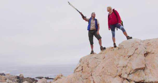 Sırt Çantalı Yürüyüş Direkleri Olan Yaşlı Çift Dağlarda Yürürken Kayalıklarda — Stok video