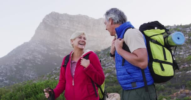Idősebb Pár Hátizsákkal Turistapóznákkal Mosolyogva Miközben Egymásra Néznek Miközben Hegyi — Stock videók