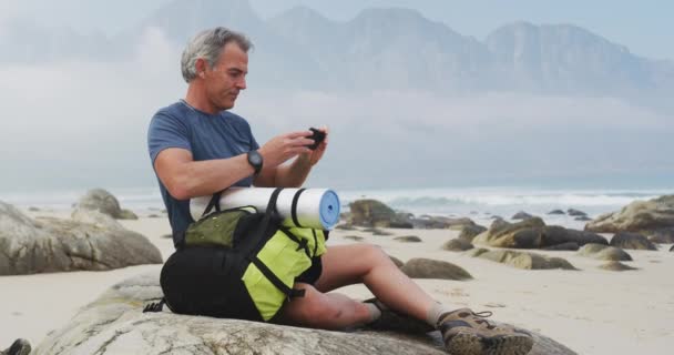 Senior Wandelaar Met Rugzak Met Behulp Van Smartphone Tijdens Het — Stockvideo