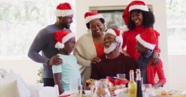 Noel Baba şapkalı Afro-Amerikan ailesi evde konuşurken ve gülümserken. Noel kutlaması geleneği konsepti